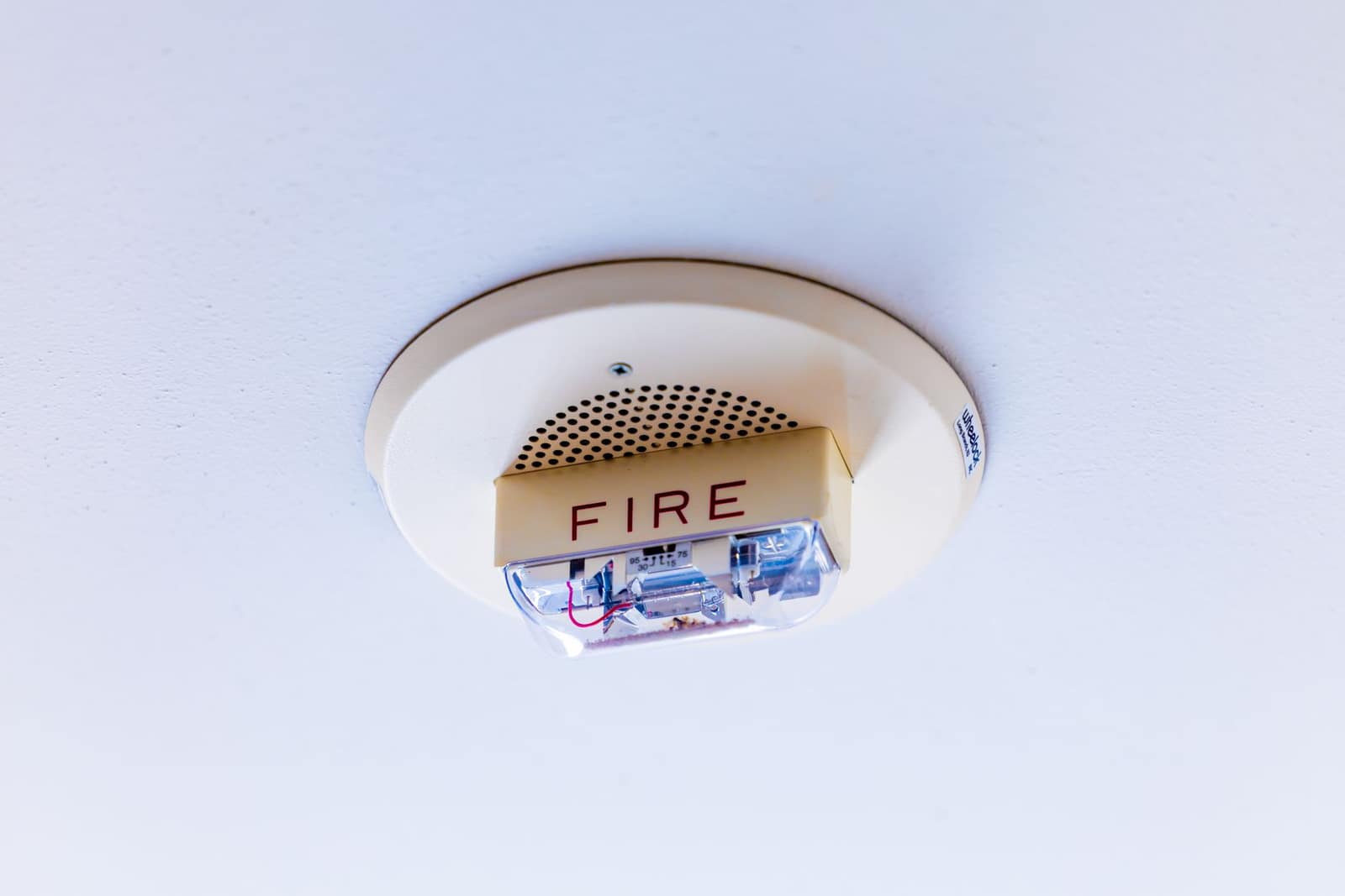 An alarm mounted on a white ceiling.