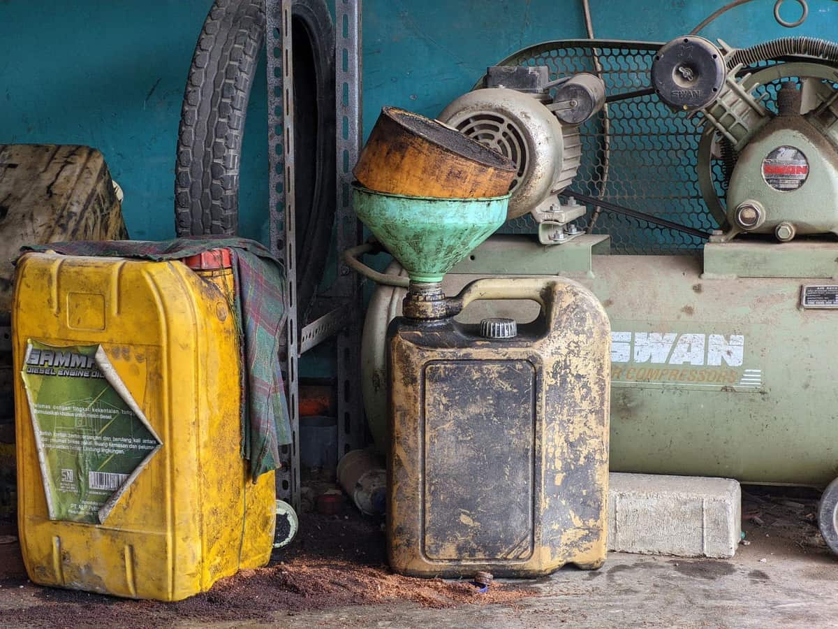 An oil bottle and funnel on a workbench.