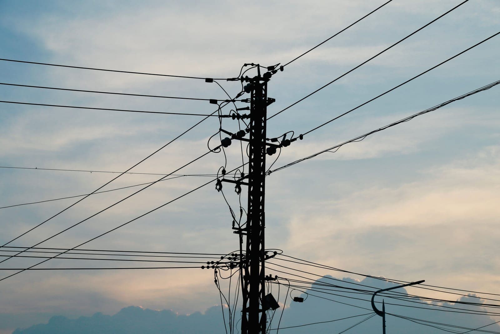 Utility power lines silhouetted against a sunset.