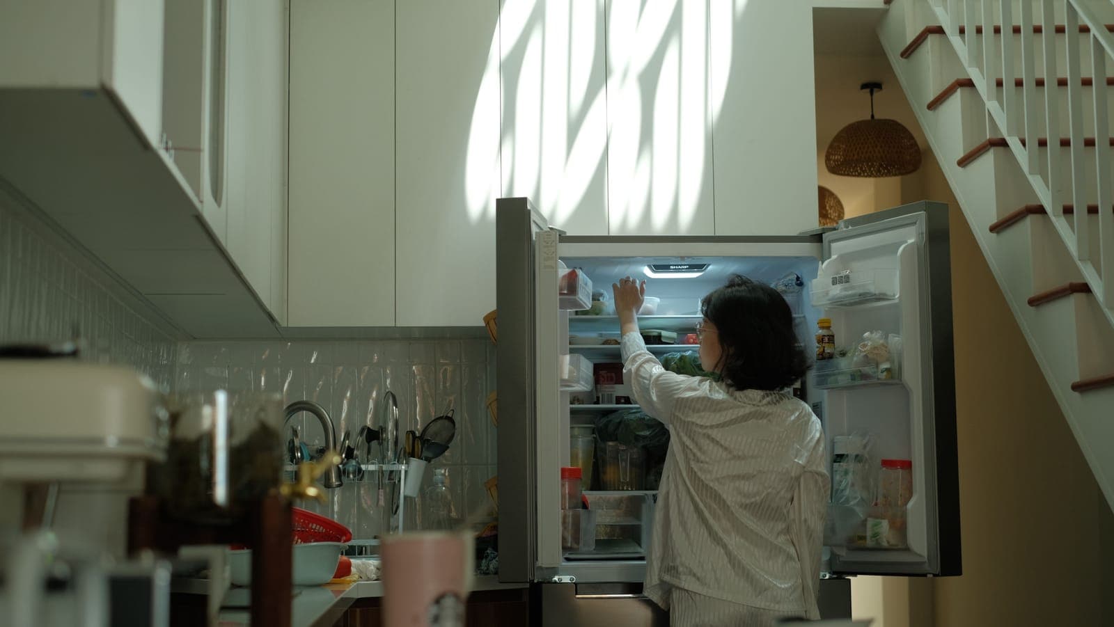 An open refrigerator lighting a dark kitchen.