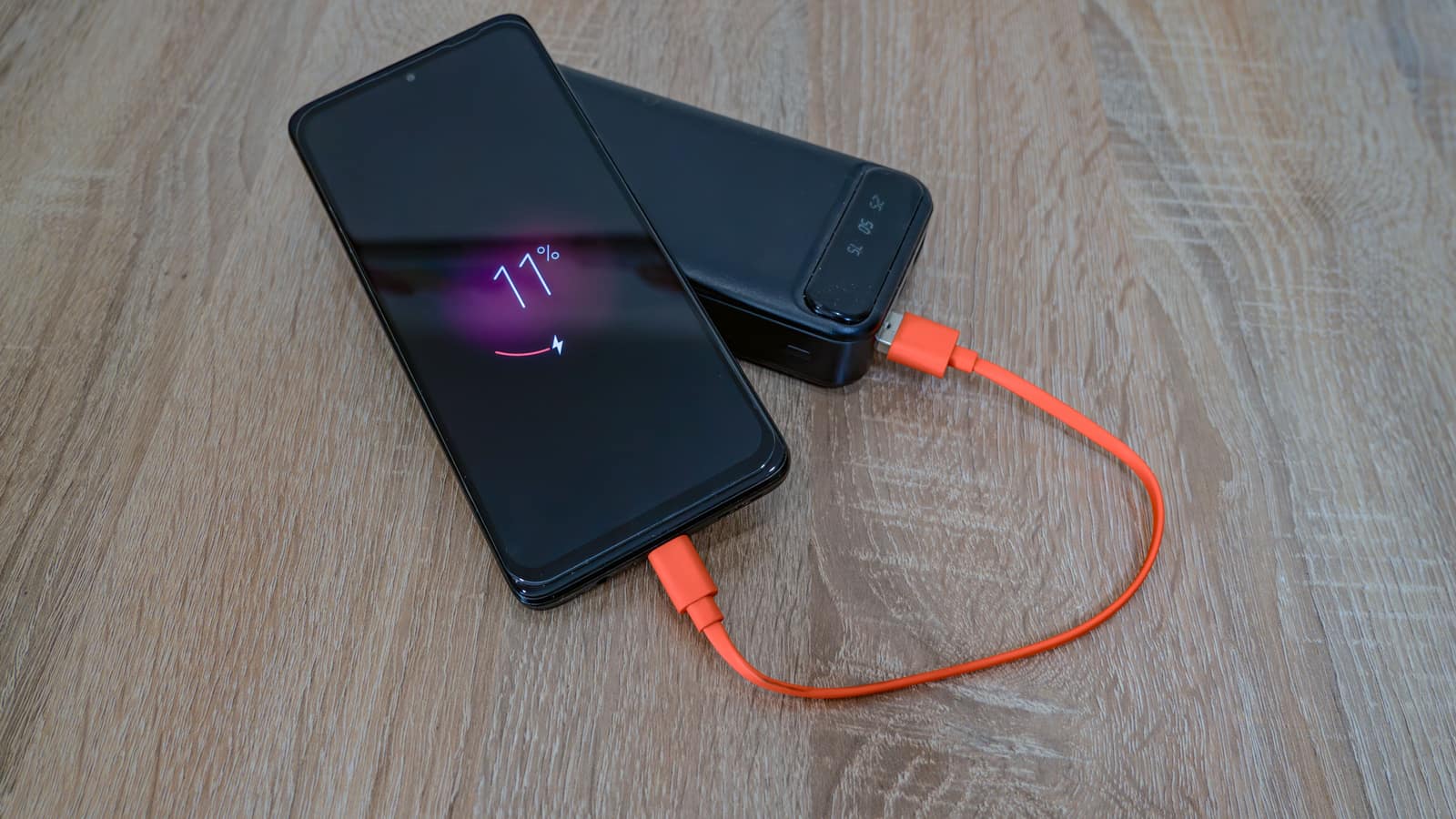 A small battery pack charging a phone on a desk.
