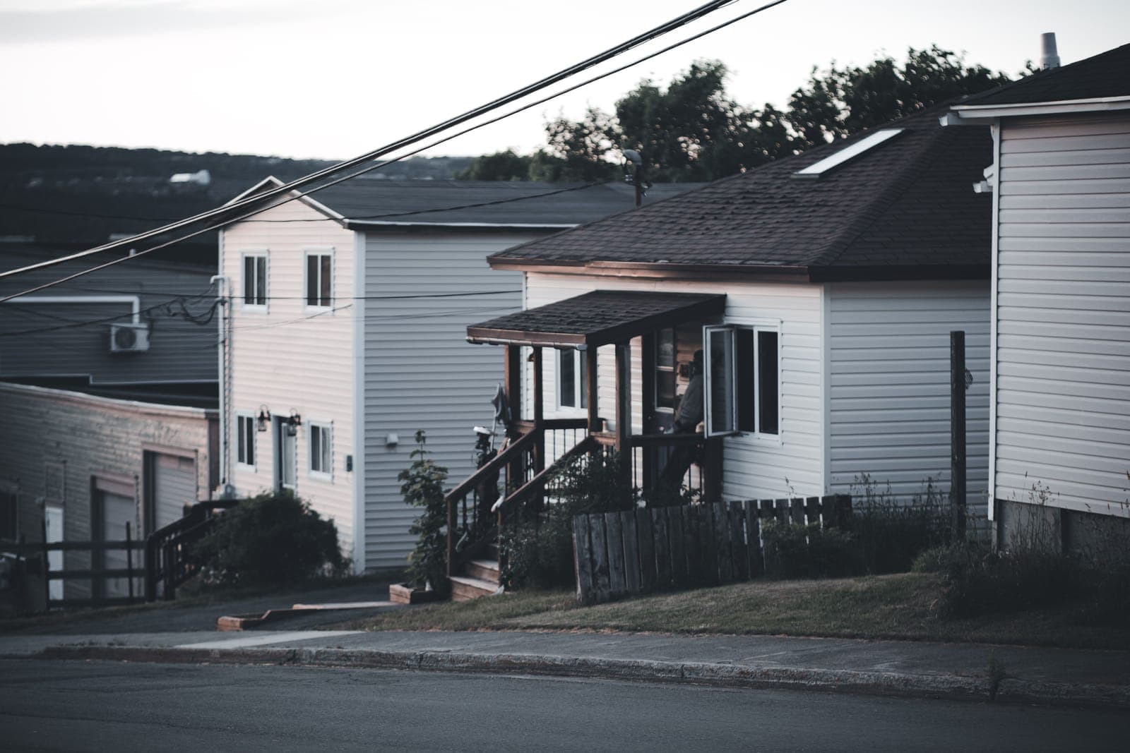 A portable generator standing on a house porch at dusk.