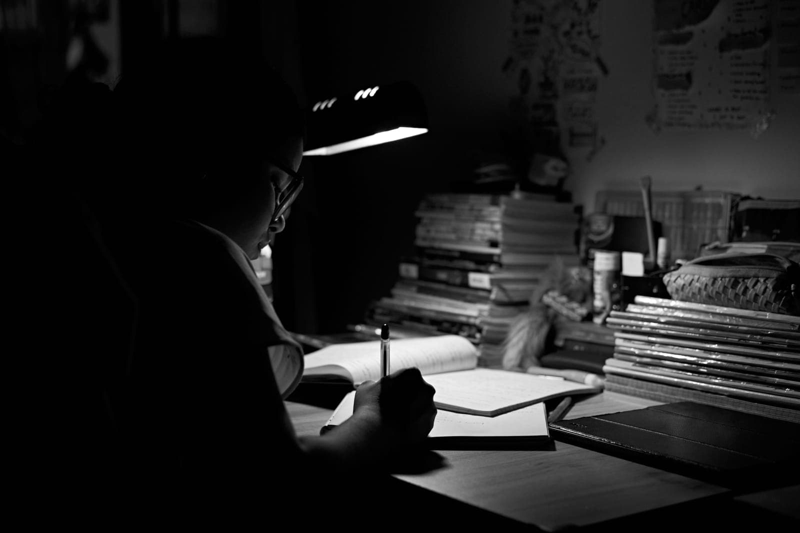 A desk with books and a lamp in a dark study.